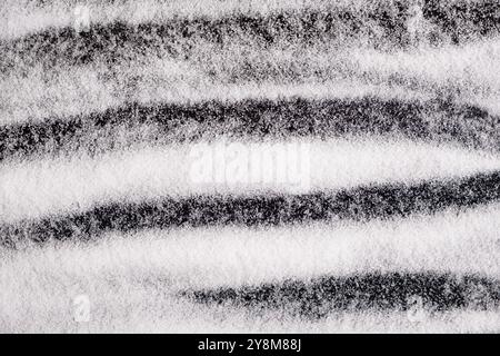 Finely ground stone white rock salt texture on black background, top view Stock Photo
