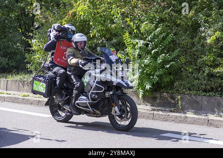 A cameraman on a motorbike rides during a bicycle race on a sunny road surrounded by green nature, Stuttgart, Baden-Wuerttemberg, Germany, Europe Stock Photo