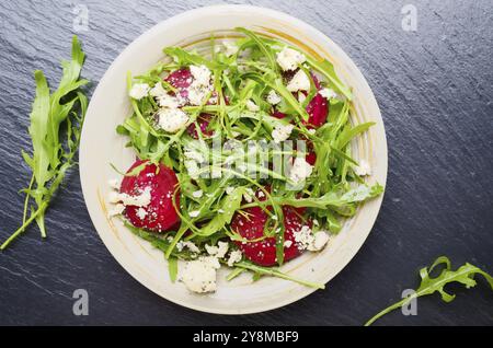 Top view at clay dish with beetroot arugula and feta cheese salad on slate stone tray closeup view Stock Photo