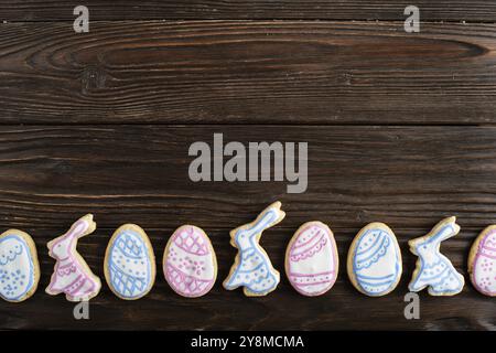 Easter frosted cookies in shape of egg, rabbit and chicken on wooden background. Flat lay with copy space Stock Photo