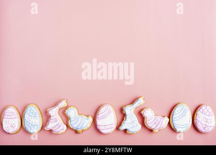 Easter frosted cookies in shape of egg, rabbit and chicken on pink background. Flat lay with copy space Stock Photo
