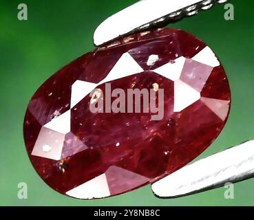 Exquisite Oval-Cut Natural Ruby Gemstone Glimmering Under Light. Stock Photo