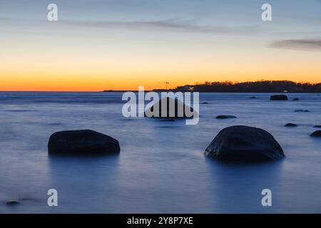 Sunset on the coast of the Baltic Sea. Stones on the shallow sea shore. Stock Photo