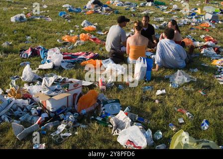 Litter UK. Waste empty beer cans, left over picnic plastic bags used to carry picnic food. Group of four young adults, sitting chatting in a circle in the middle of  peoples discarded leftovers. And complety unaware of their surroundings. Th Derby horse racing. On the Hill, Epsom Downs Surrey England 2007 2000s UK HOMER SYKES Stock Photo