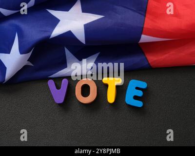 The flag of the USA lying on a chalkboard with the letters VOTE spelled on it. Close up. Stock Photo