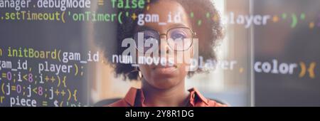 Website header shot of serious female software developer of Black ethnicity reflecting in computer screen with code lines running Stock Photo