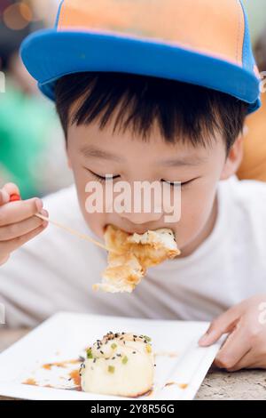 A young boy eating dumplings Stock Photo