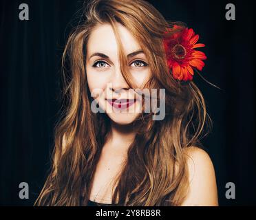 girl with long blond hair playfully looks holding a pumpkin in her hands. concept photo for halloween. on a black background Stock Photo