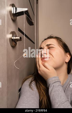 The girl is holding a thread to pull out a tooth. Extraction of a tooth ...
