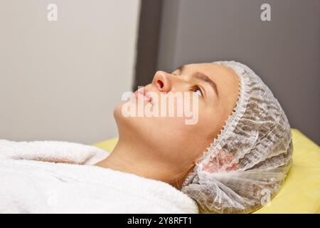 Preparation for procedures in the cosmetologist s office. Beautician in gloves, putting on a hat. Stock Photo