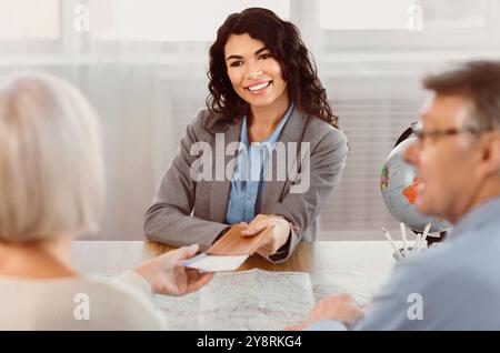 Woman giving tickets to happy mature couple Stock Photo