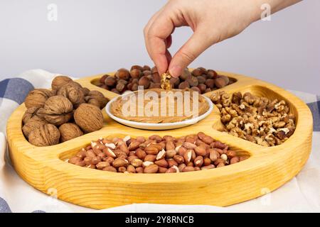 Creamy peanut butter, peanut butter in an open glass jar in the center of a peanut food background. Peanuts in shell, peeled peanuts on a white Stock Photo