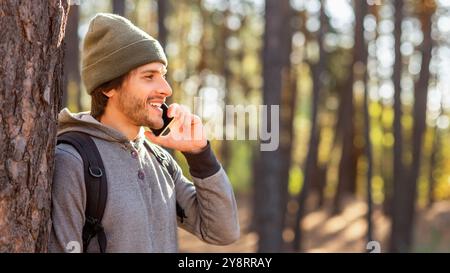Happy young man backpacker talking on phone while hiking Stock Photo