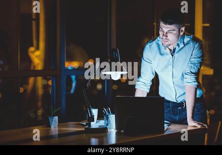 Businessman Working On Laptop Standing In Office Late At Night Stock Photo
