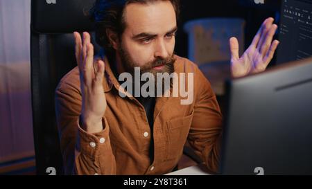 Disappointed computer scientist puzzled after being unable to remove all bugs while coding on workstation desktop. Teleworking IT specialist confused by troubling script errors, camera B close up Stock Photo