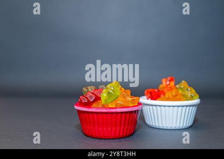 Colourful and small gel candies in small bowls. Grey ground and background. Stock Photo