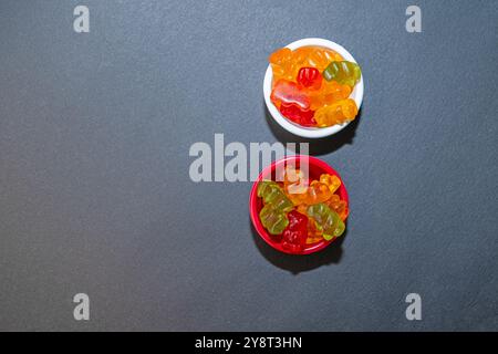 Colourful and small gel candies in small bowls. Grey ground and background. Top view. Stock Photo