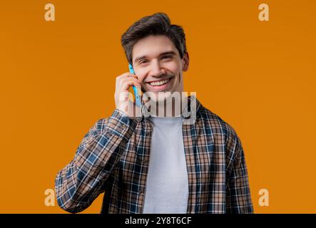 Smiling positive man talking by phone, smiling. Mature guy on yellow background. Stock Photo