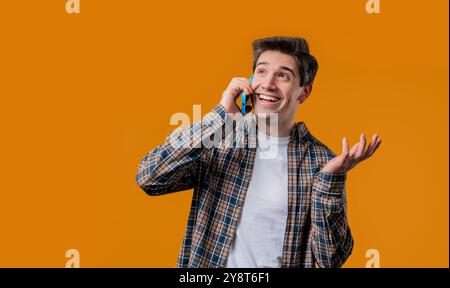 Smiling positive man talking by phone, smiling. Mature guy on yellow background. Stock Photo