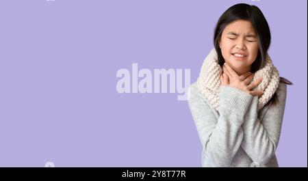 Ill Asian girl with sore throat on lilac background with space for text Stock Photo