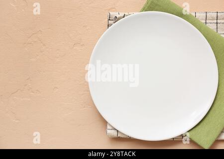 Table setting with plate and napkins on beige background Stock Photo