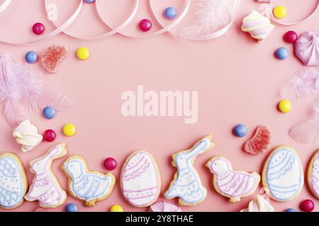 Candies and Easter frosted cookies in shape of egg chicken and rabbit on pink background. Flat lay mockup with copy space Stock Photo