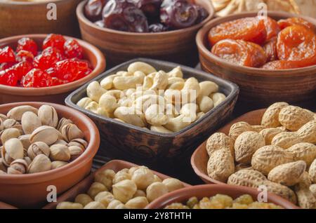 Different nuts and dried fruits in bowls on kitchen table Stock Photo