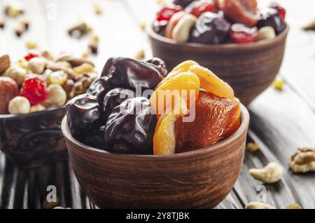 Dried dates and apricots in clay bowl on wooden kitchen table closeup Stock Photo