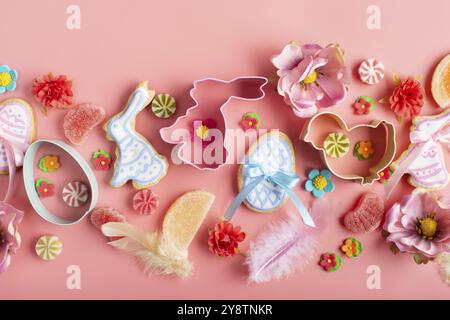 Easter frosted cookies in shape of egg chicken and rabbit, sugar sprinkles, candies, cookie cutters on pink background. Flat lay mockup Stock Photo