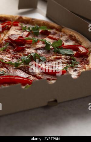 Large Pizza with pepperoni and bell peppers in open carton box closeup view Stock Photo