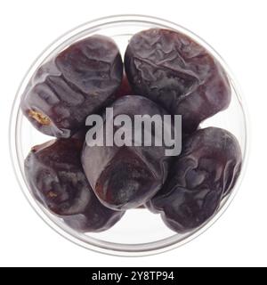 Dried dates in glass bowl isolated on white background flat lay closeup view Stock Photo