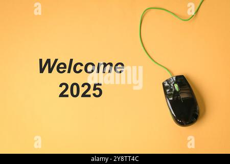 Welcome 2025 text next to computer mouse on yellow background. New year. Stock Photo