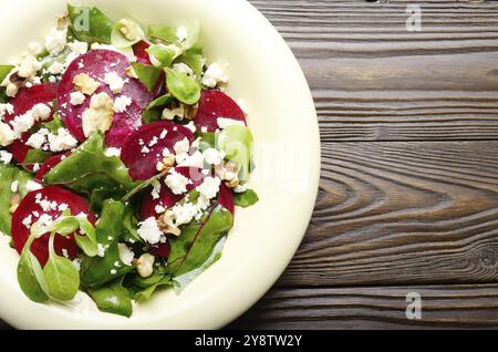 Top view at mediterranean roasted beet salad with walnuts feta cheese and mash leaves on wooden table Stock Photo