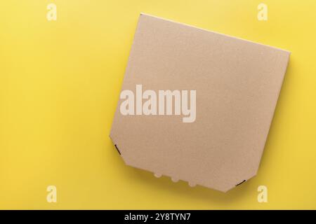 Pizza closed carton box on uniform yellow background flat lay mockup with blank space Stock Photo