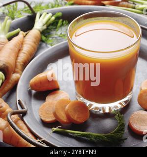 Vegetarian background of old fashioned tray with fresh organic carrots and juice on kitchen wooden table Stock Photo