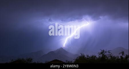 Summer electrical storm produces a lightning bolt illuminating a valley in rural Arizona Stock Photo