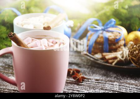 Christmas background of two mugs of hot chocolate with marshmallows, spruce branch and tray with gingerbread cookies on wooden table Stock Photo