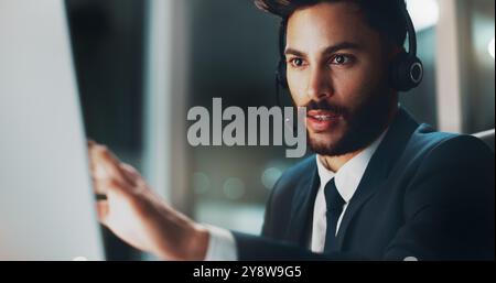 Customer support, computer and man in office at night for international technical service consultation online. Headset, tech and male call center Stock Photo