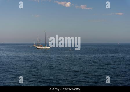 A beautiful sailboat is gracefully floating gently on top of a large and expansive body of water surrounded by natures beauty Stock Photo