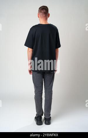 Back view of a casual man standing on gray backgorund in studio Stock Photo