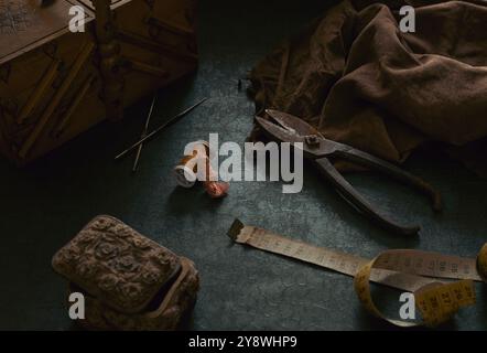 Still life composed from tailor's old tools and accessories such as scissors, measuring tape, leather fabric, sewing box in scene. Sewing supplies in Stock Photo