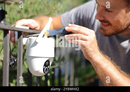 Happy man installing wifi security camera in a house garden Stock Photo