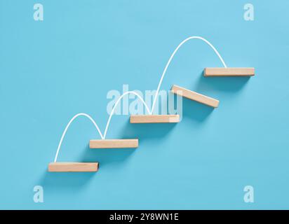 Overcoming obstacles and problem solving in business or career growth concept. White line forming increasing graph over wooden blocks on blue backgrou Stock Photo