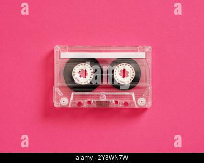 Transparent audio cassette tape on a pink background evokes nostalgia for retro music lovers, symbolizing a blend of old-school technology and timeles Stock Photo
