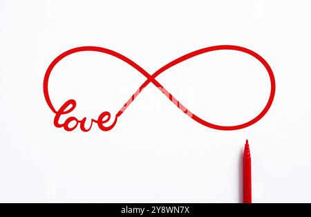 Red infinity symbol drawn with a red marker on a white background representing the concept of eternal love Stock Photo