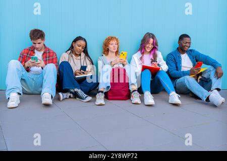 Diverse young people sitting outdoors using smartphones Stock Photo