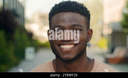 Close up male face happiness expression portrait African American happy smiling guy in city laugh funny reaction enjoy biracial man smile toothy white Stock Photo