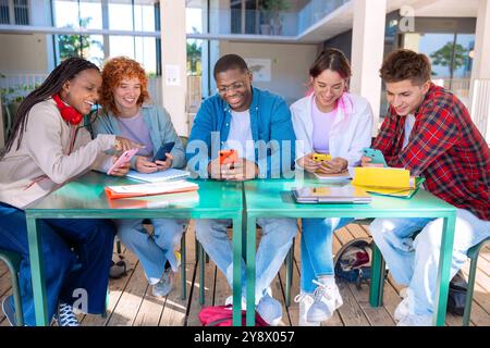 A diverse group of students collaborating with mobiles at the table Stock Photo