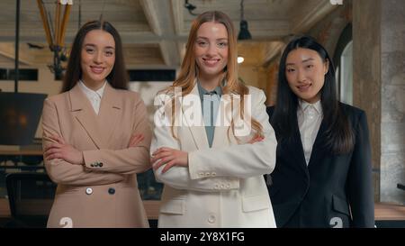 Business women three multiracial girls multiethnic females diversity businesswomen Asian Korean Japanese Chinese Caucasian partners formal wear posing Stock Photo
