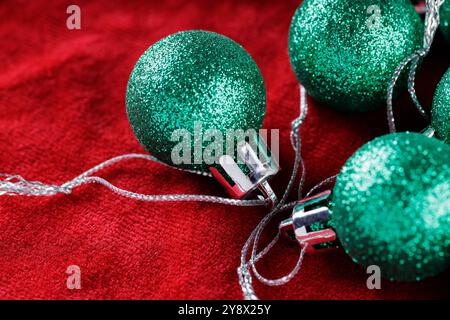 Glittery Green Christmas Decorations on Red Fabric Background, Close-Up Stock Photo